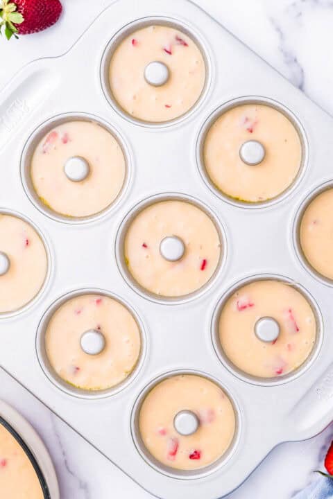 donut batter piped into a metal donut pan