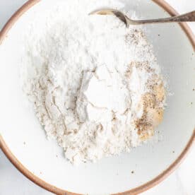 flour, cornstarch, and seasonings in a shallow bowl with a metal spoon