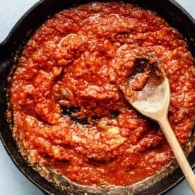 tomato sauce in a cast iron skillet with a wooden spoon