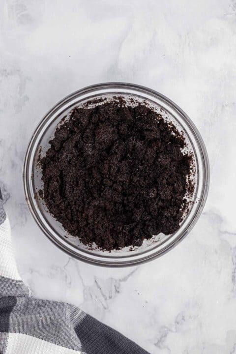 oreo crumbs mixed with butter in a clear mixing bowl