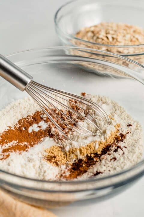 dry ingredients and spices in a clear bowl with a metal whisk