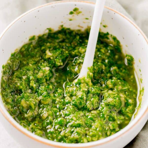 basil pesto in a small gold rimmed bowl with a white spoon