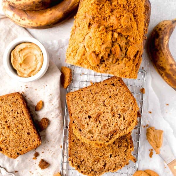 slices of biscoff bread on a metal wire rack next to ripe bananas and biscoff cookies scattered around