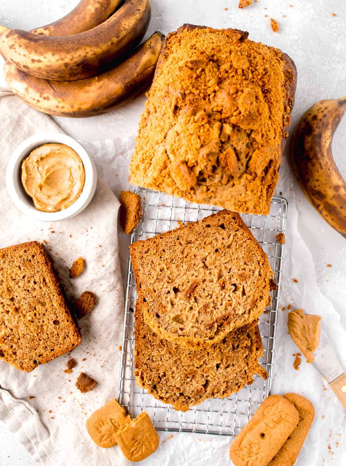 slices of biscoff bread on a metal wire rack next to ripe bananas and biscoff cookies scattered around