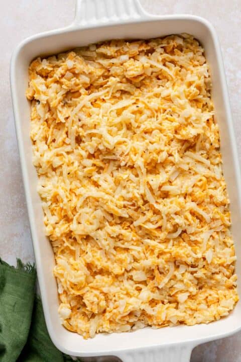 unbaked cheesy hashbrown casserole mixture in a white casserole dish