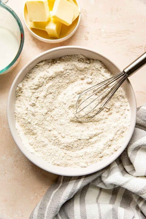 flour and other dry ingredients mixed together in a bowl with a metal whisk
