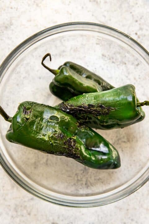 charred poblano peppers in a clear bowl