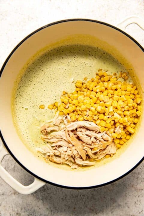 shredded chicken and frozen corn is added to the soup in the dutch oven