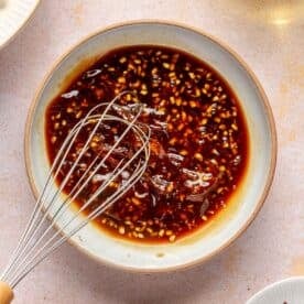 a metal whisk whisking ingredients for general tso's sauce in a bowl