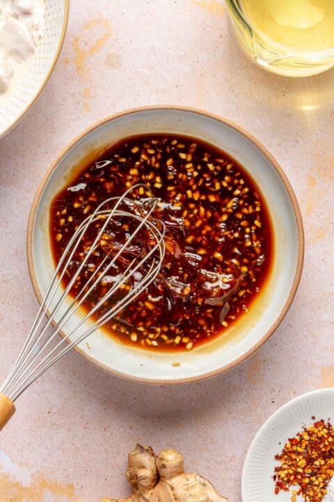 a metal whisk whisking ingredients for general tso's sauce in a bowl