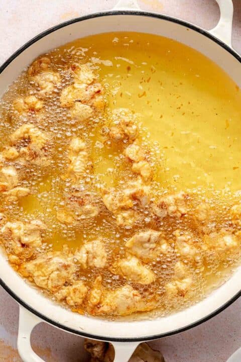 frying battered chicken in a large pot of oil