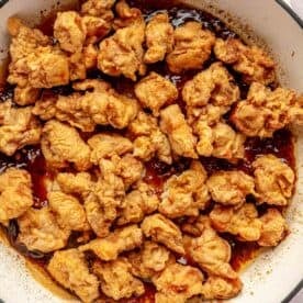 fried chicken added to the general tso's sauce in a cast iron skillet
