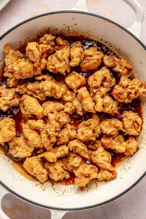 fried chicken added to the general tso's sauce in a cast iron skillet