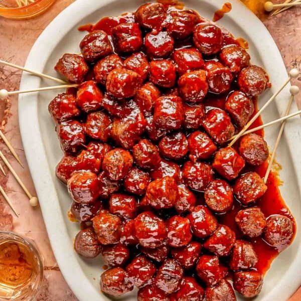 grape jelly meatballs on a large white platter with numerous toothpicks