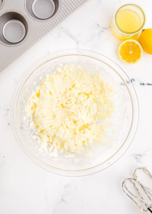 butter and sugar creamed together in a clear bowl with electric mixer whisks next to the bowl