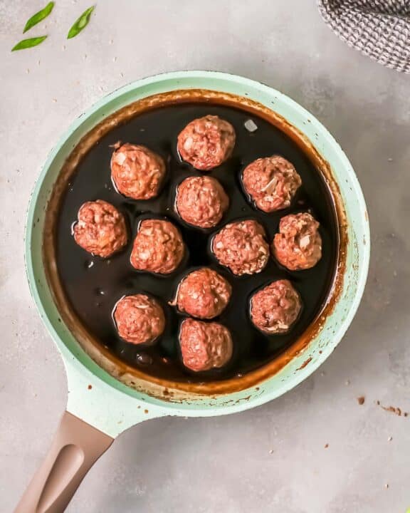 cooked meatballs placed into a saucepan with sauce