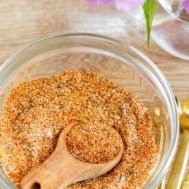 adobo seasoning in a clear bowl with a wooden spoon