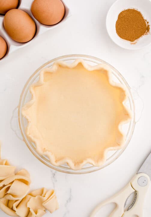 pie crust in a clear baking dish pressed into a scalloped pattern