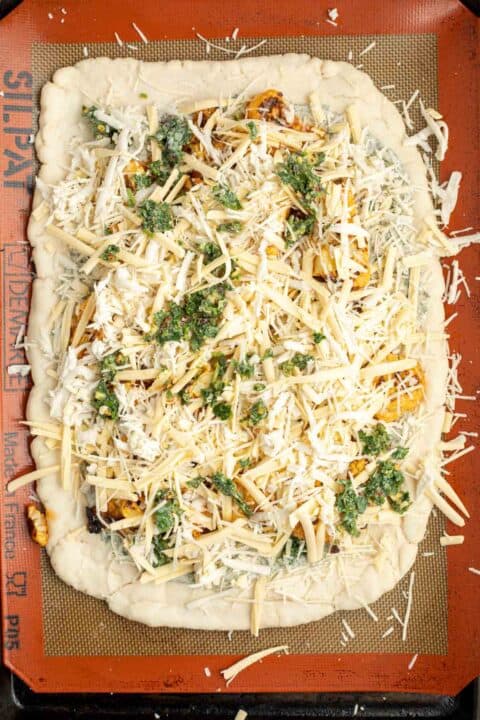 buffalo cauliflower pizza assembled on top of a silicone baking mat