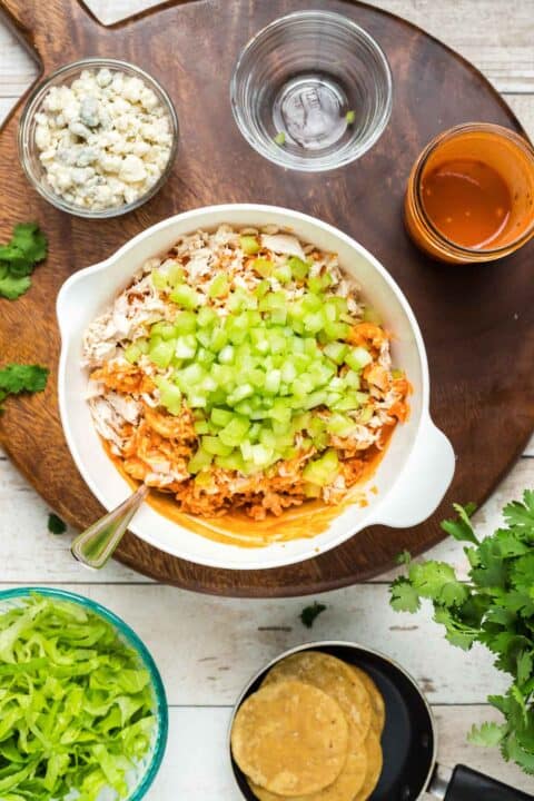 buffalo chicken mixture with fresh celery in a white bowl