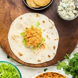 assembling the buffalo chicken crunchwrap on a large flour tortilla