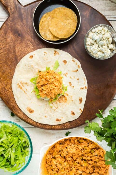 assembling the buffalo chicken crunchwrap on a large flour tortilla