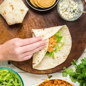 folding the buffalo chicken crunchwrap towards the center of the flour tortilla and filling
