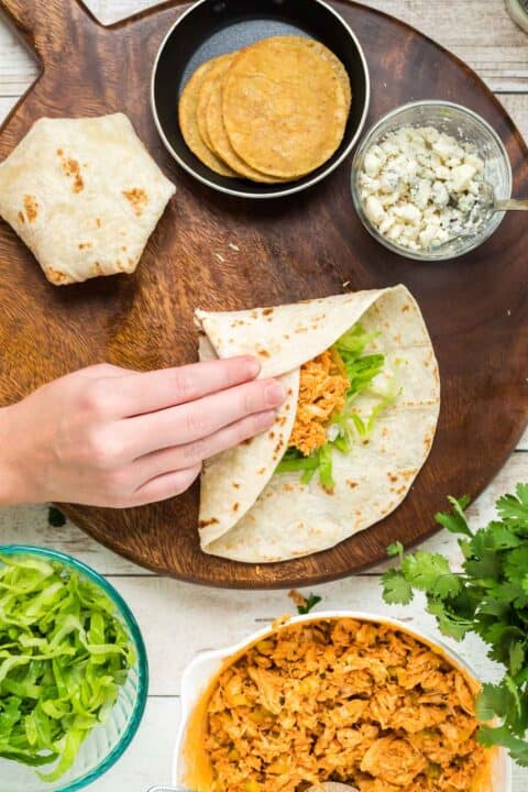 folding the buffalo chicken crunchwrap towards the center of the flour tortilla and filling