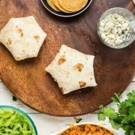 the buffalo chicken crunchwrap is seam-side down on the wooden cutting board