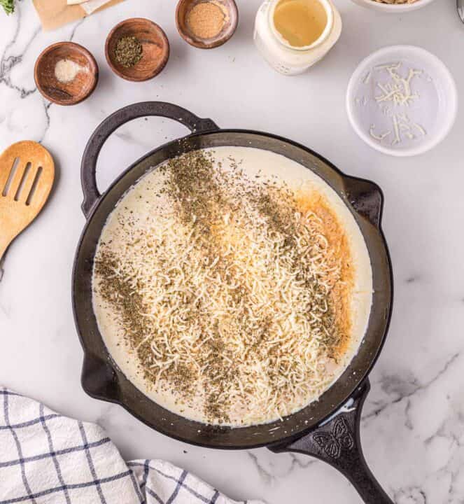 cheese and seasonings added to a cast iron skillet