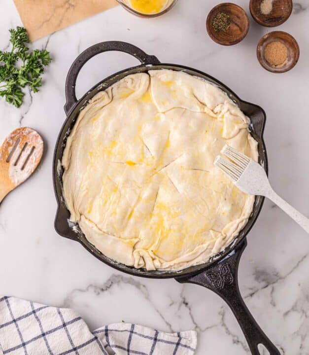 egg wash brushed on top of puff pastry in a cast iron skillet