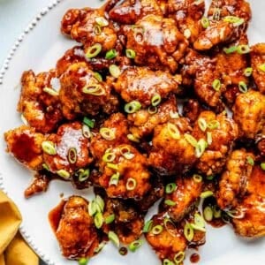 chipotle honey chicken poppers on a large white plate garnished with fresh green onions