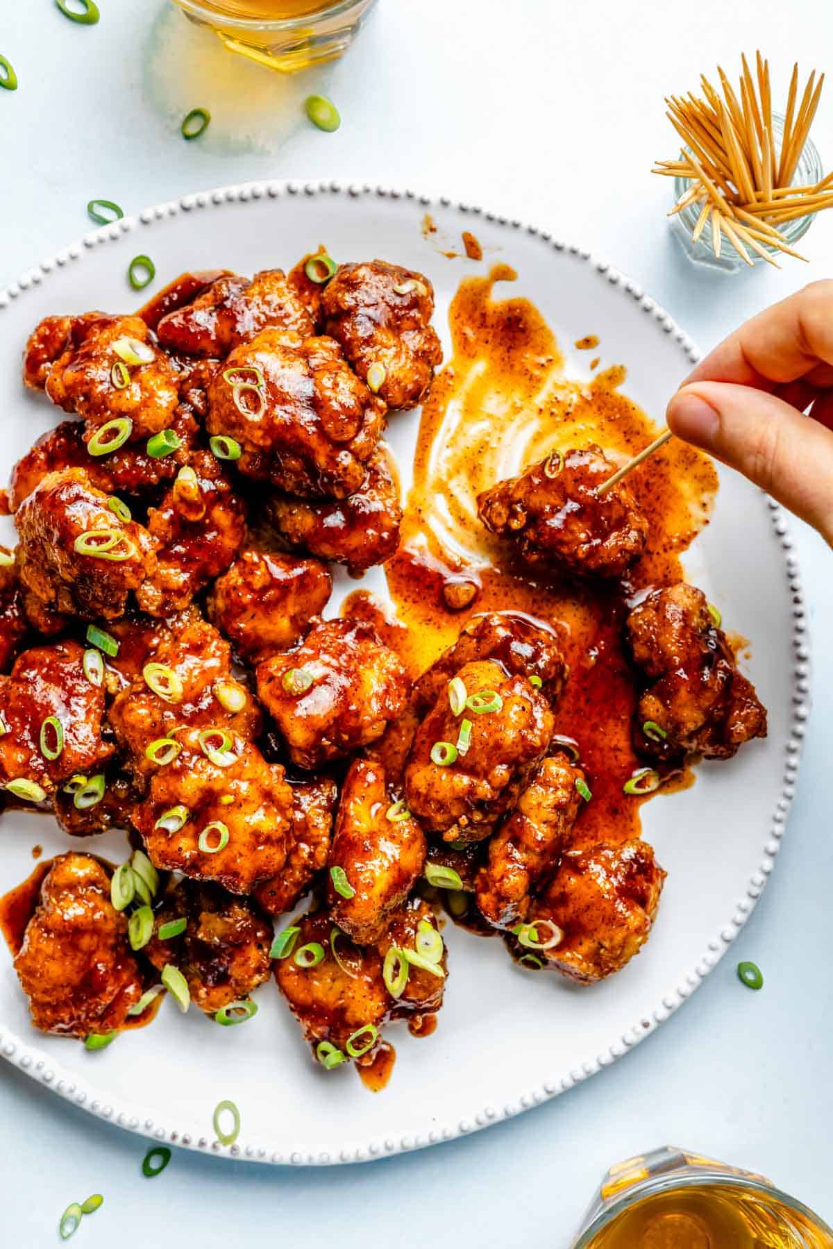 chipotle honey chicken poppers with a hand and toothpick taking a chicken popper
