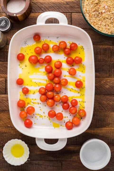 cherry tomatoes in a baking dish with olive oil and black pepper