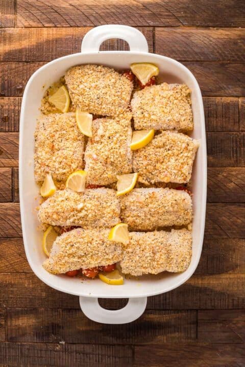 everything crusted cod in a baking dish with fresh lemon wedges