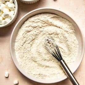 a bowl of flour with a silicone whisk in the center