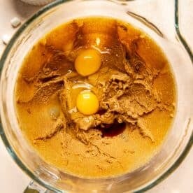 two eggs and vanilla extract added to a stand mixer bowl with creamed butter and sugar