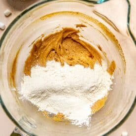 flour is added to a stand mixer bowl along with creamed butter and sugar