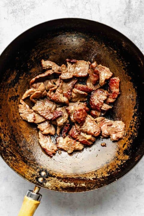 seared and browned thinly sliced flank steak pieces in a wok