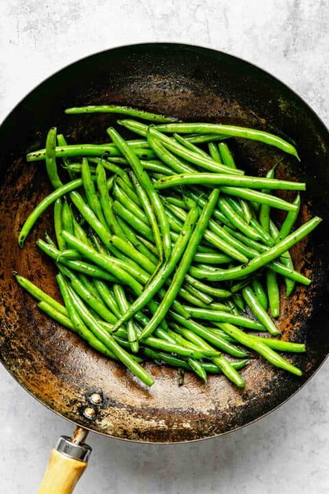 charred and cooked green beans in a wok