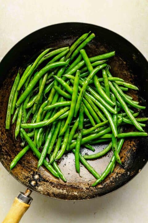 green beans being charred and cooked in a wok