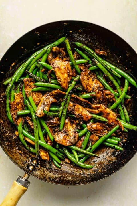 stir fry sauce has been added to chicken and green beans in the wok