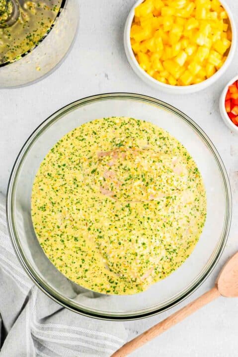 marinade for mojo chicken poured on top of chicken breasts in a clear bowl