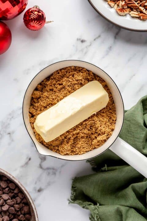 a stick of butter is on top of brown sugar in a small saucepan