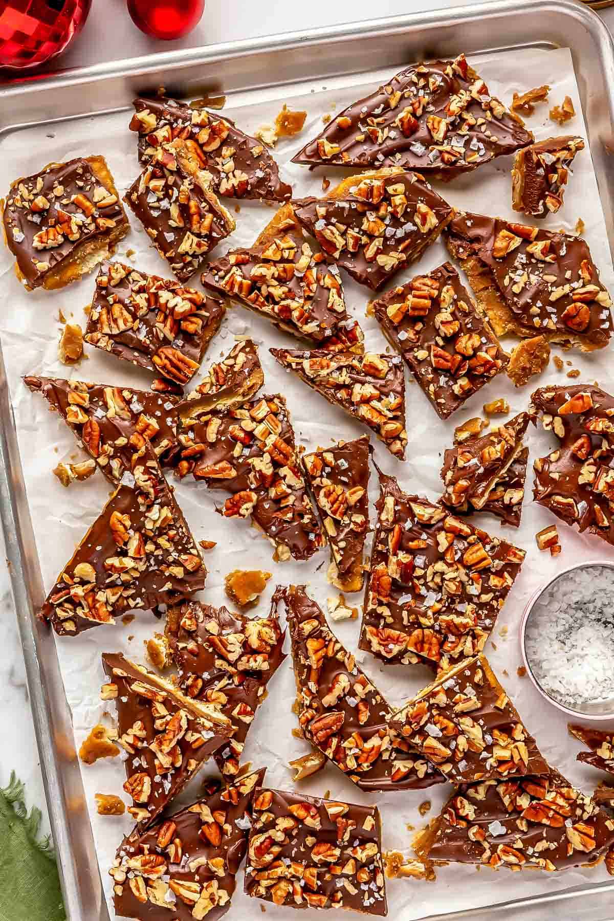 saltine toffee broken into several pieces on parchment paper