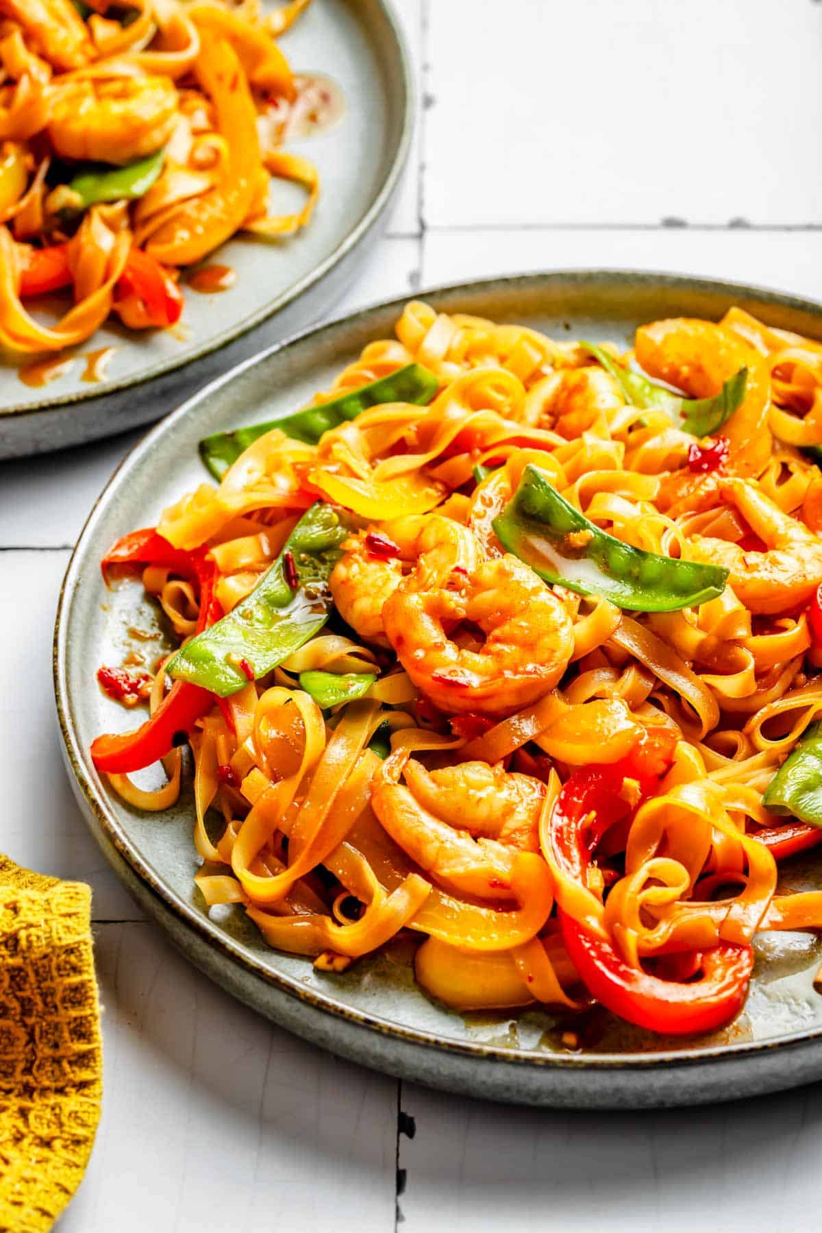 shrimp noodle stir fry on a rimmed plate