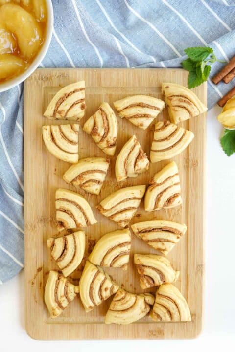 cinnamon rolls cut into triangles on a wooden cutting board