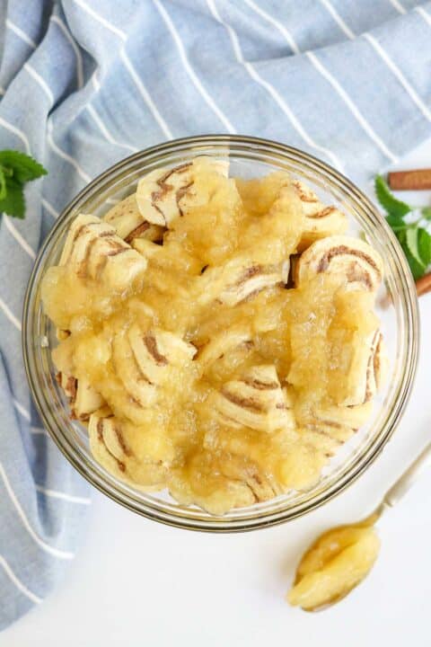 apple pie filling and cut up cinnamon rolls in a clear bowl