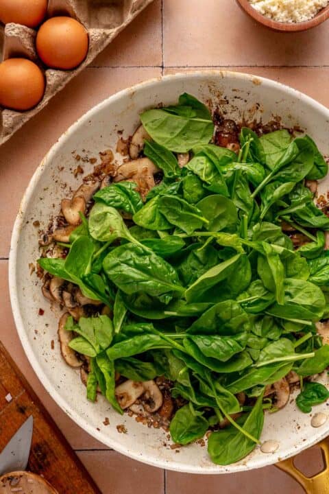 baby spinach leaves added on top of mushroom and shallot mixture in the skillet