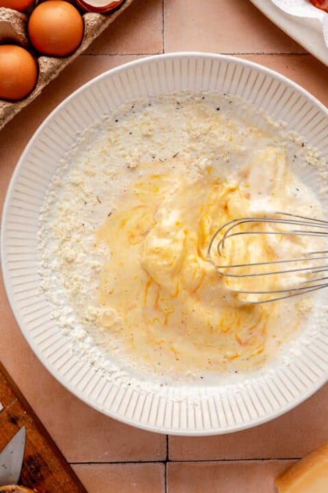 whisking together egg mixture in a white bowl